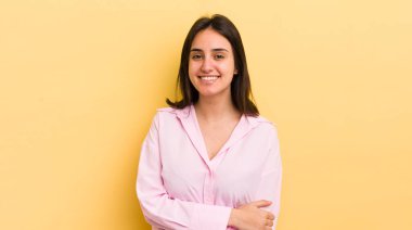 Genç İspanyol kadın utangaç ve neşeli bir şekilde gülüyor, arkadaş canlısı ve olumlu ama güvensiz bir tavırla.