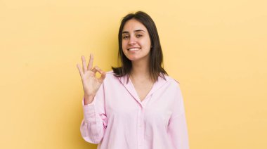 Genç İspanyol kadın kendini mutlu, rahat ve tatmin olmuş hissediyor. Onayını iyi bir hareketle gösteriyor. Gülümsüyor.