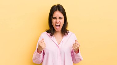 Genç İspanyol kadın sinirli, sinirli, kızgın bakışlarla ve sıkı yumruklarla agresif bir şekilde bağırıyor.