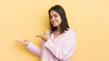 Genç İspanyol kadın gülümsüyor, mutlu, kaygısız ve tatmin olmuş hissediyor, fotokopi alanındaki konsepte ya da fikre işaret ediyor.
