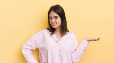 Genç İspanyol kadın gülümsüyor, kendinden emin, başarılı ve mutlu hissediyor, fotokopi alanında fikir veya konsept gösteriyor.