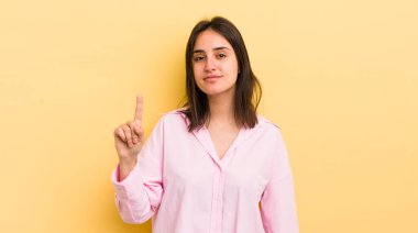 Genç İspanyol kadın gülümsüyor ve arkadaş canlısı görünüyor, bir numara veya ilk eli önde, geriye doğru sayıyor.