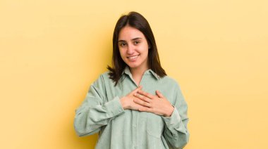 Genç İspanyol kadın romantik, mutlu ve aşık, neşeyle gülümsüyor ve kalbe yakın el ele tutuşuyor.