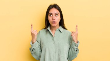 Genç İspanyol kadın şaşkınlık içinde ve ağzı açık. Şok olmuş ve şaşırmış bir bakışla yukarı bakıyor.