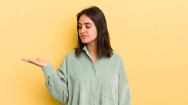 Genç İspanyol kadın kendini mutlu hissediyor ve gülümsüyor. Yan taraftaki bir nesneye ya da konsepte bakıyor.