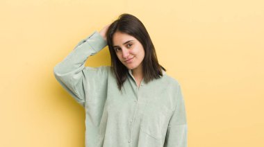 Genç İspanyol kadın neşeli ve sıradan bir şekilde gülümsüyor, olumlu, mutlu ve kendinden emin bir bakışla yumruk yumruğa.