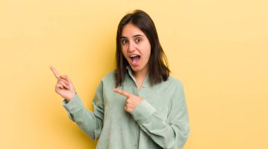 Genç İspanyol kadın sevinçli ve şaşırmış hissediyor. Şok olmuş bir ifadeyle gülümsüyor ve bir tarafı işaret ediyor.