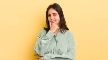 Genç İspanyol kadın ciddi, düşünceli ve güvensiz görünüyor, bir kolu çapraz ve çene üzerinde, seçenekleri tartıyor