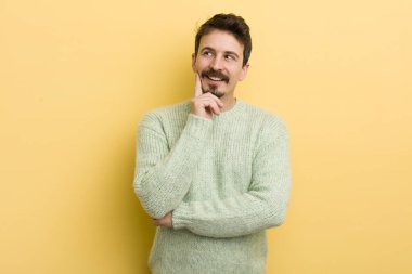 Genç İspanyol adam mutlu bir şekilde gülümsüyor ve hayal kuruyor ya da şüphe ediyor.