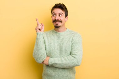 Genç İspanyol adam mutlu bir şekilde gülümsüyor ve yan bakıyor, merak ediyor, düşünüyor ya da bir fikri var.