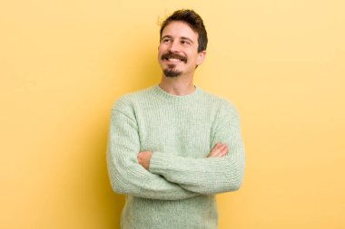 Genç İspanyol adam mutlu, gururlu ve umutlu hissediyor, merak ediyor ya da düşünüyor, çapraz kollarla boşluğu doldurmaya çalışıyor.