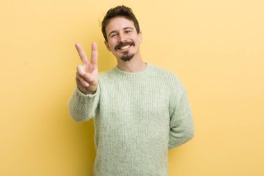 Genç İspanyol adam gülümsüyor ve mutlu görünüyor, kaygısız ve olumlu, zafer ya da barışı simgeliyor.