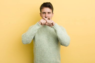 Latin asıllı genç adam ciddi görünüyor ve iki parmağının önde olması hoşnutsuzca karşılıyor. Sessizlik istiyor.