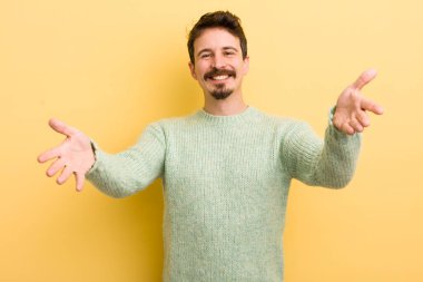 Genç İspanyol adam neşeyle gülümsüyor sıcak, dostça, sevgi dolu bir kucak veriyor, mutlu ve sevimli hissediyor.