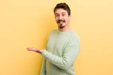 Genç İspanyol adam neşeyle gülümsüyor, mutlu hissediyor ve fotokopi uzayda bir kavram gösteriyor.