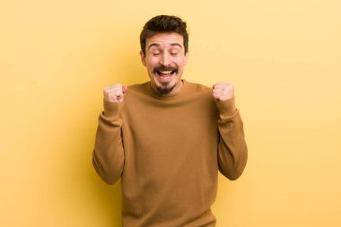 Genç İspanyol adam son derece mutlu ve şaşırmış görünüyor, başarıyı kutluyor, bağırıyor ve zıplıyor.