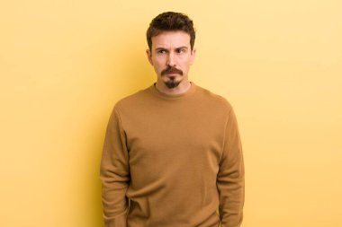 Genç İspanyol bir adam üzgün, üzgün ya da kızgın ve olumsuz bir tavırla taraflara bakıyor, anlaşmazlıkla çatışıyor.