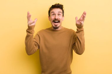 Genç İspanyol adam kendini mutlu, şaşkın, şanslı ve şaşırmış hissediyor. Zaferi kutlarken iki eli havada.