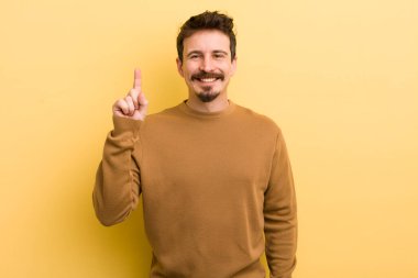 Genç İspanyol adam mutlu bir şekilde gülümsüyor, tek eliyle uzayı işaret ediyor.