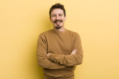 Kollarını kavuşturup gülümseyen mutlu, gururlu ve tatmin olmuş genç bir İspanyol gibi görünüyor.