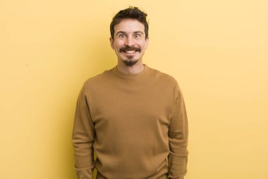 Genç İspanyol adam mutlu ve şapşal görünüyor. Geniş, eğlenceli, deli gülüşü ve gözleri açık.