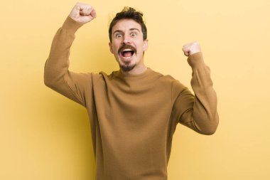 Genç İspanyol adam muzaffer bir şekilde bağırıyor. Heyecanlı, mutlu ve şaşırmış görünüyor. Kutlama yapıyor.