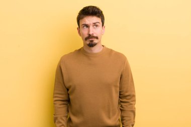 Genç İspanyol bir adam kafası karışmış ve şaşkın görünüyor, merak ediyor veya bir sorunu çözmeye çalışıyor veya düşünüyor.