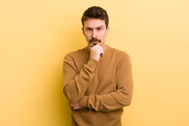 Genç İspanyol adam ciddi görünüyor, kafası karışık, kararsız ve düşünceli, seçenekler ya da seçimler arasında şüpheci