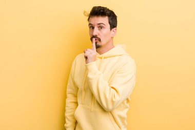Genç İspanyol bir adam sessizlik ve sessizlik istiyor, parmaklarıyla ağzının önünde işaret ediyor, 