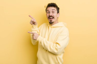 Genç İspanyol adam sevinçli ve şaşırmış hissediyor, şok olmuş bir ifadeyle gülümsüyor ve yan tarafı işaret ediyor.