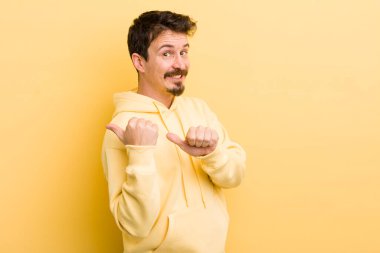 Genç İspanyol adam neşeyle gülümsüyor ve yan taraftaki fotokopi alanını işaret ediyor, mutlu ve tatmin olmuş hissediyor.