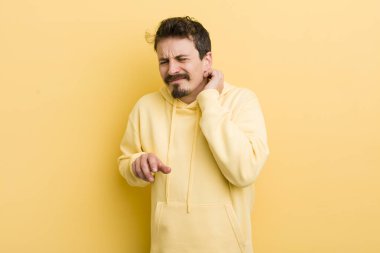 Genç İspanyol bir adam stresli, hayal kırıklığına uğramış ve yorgun, endişeli ve sorunlu bir bakışla boynunu ovalıyor.