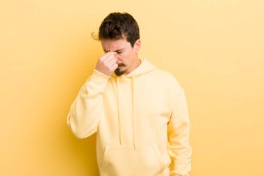 Genç İspanyol adam stresli, mutsuz ve hayal kırıklığına uğramış, alınına dokunmuş ve şiddetli baş ağrısı çeken.