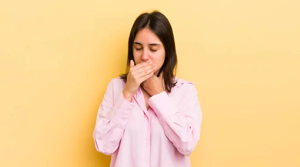 young hispanic woman feeling ill with a sore throat and flu symptoms, coughing with mouth covered