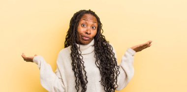 siyah güzel kadın şaşkın ve şaşkın hissediyor, şüpheci, farklı seçenekleri tartıyor veya komik bir ifadeyle seçiyor.