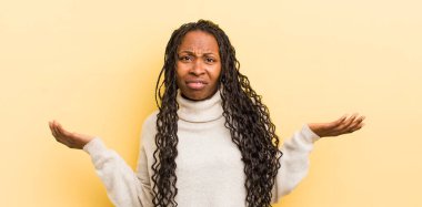 Şaşkın, kafası karışmış ve stresli görünen siyah güzel kadın farklı seçenekler arasında merak ediyor, kararsız hissediyor.