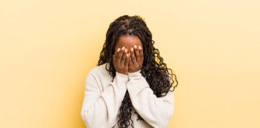 Siyah güzel bir kadın üzgün, hayal kırıklığına uğramış, gergin ve depresif, iki eliyle yüzünü örten, ağlayan