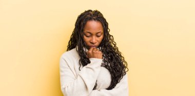 Siyah güzel bir kadın ciddi, düşünceli ve endişeli, elleri çenesine bastırılmış bir şekilde yan bakıyor.