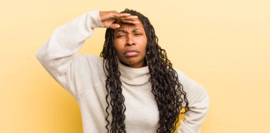 Siyah güzel kadın şaşkınlık ve şaşkınlık içinde bakıyor, el üstünde uzak bakıyor, izliyor ya da arıyor