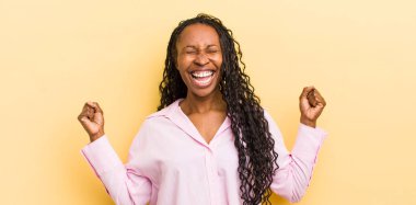 siyahi güzel kadın çok mutlu ve şaşırmış görünüyor, başarıyı kutluyor, bağırıyor ve zıplıyor.