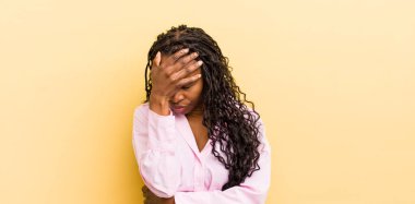 Siyah, güzel bir kadın stresli, utanmış ya da üzgün görünüyor, baş ağrısı var, yüzünü eliyle kapatıyor.