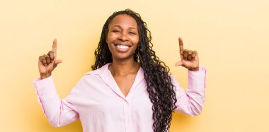 siyah güzel bir kadın kendi gülüşünü çiziyor, iki eliyle, pozitif ve mutlu görünüyor, sağIık kavramı.