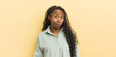 Siyah güzel bir kadın, kafası karışık ve şüpheli hissediyor, merak ediyor ya da karar vermeye çalışıyor.
