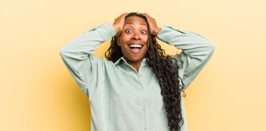 Siyah güzel bir kadın el ele tutuşuyor, ağzı açık, son derece şanslı, şaşırmış, heyecanlı ve mutlu hissediyor.