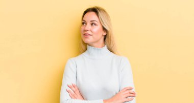 Sarışın, beyaz kadın mutlu, gururlu ve umutlu, merak ediyor ya da düşünüyor, çapraz kollarla fotokopi çekmeye çalışıyor.