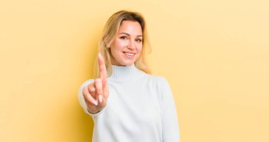 Sarışın, beyaz bir kadın gururla gülümsüyor ve bir numaralı pozunu başarıyla veriyor, kendini lider gibi hissediyor.