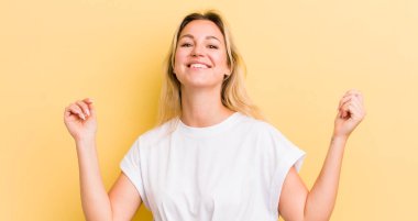 Sarışın, beyaz kadın son derece mutlu ve şaşırmış görünüyor, başarıyı kutluyor, bağırıyor ve zıplıyor.