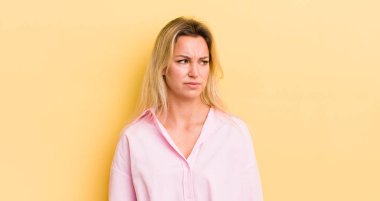 Sarışın, beyaz bir kadın üzgün, üzgün ya da kızgın. Olumsuz bir tavır sergiliyor, anlaşmazlık içinde kaşlarını çatıyor.