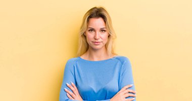 Sarışın, beyaz bir kadın hayal kırıklığına uğramış, hayal kırıklığına uğramış, ciddi görünüyor, kızgın ve kollarını kavuşturmuş.