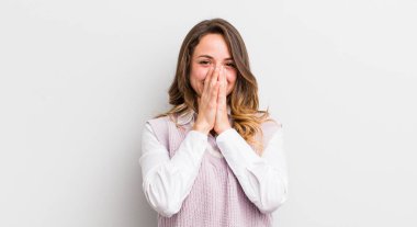 Güzel bir kadın mutlu, neşeli, şanslı ve şaşkın görünüyor. İki eliyle ağzını kapatıyor.